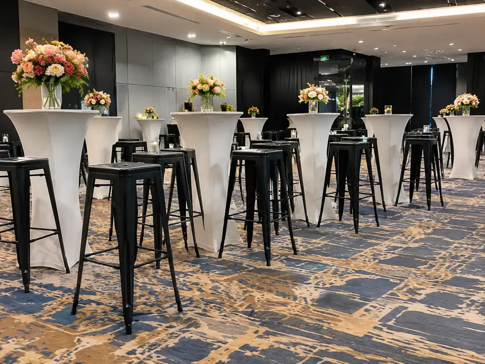 Black bar stools beside white cocktail tables in a ballroom reception setup