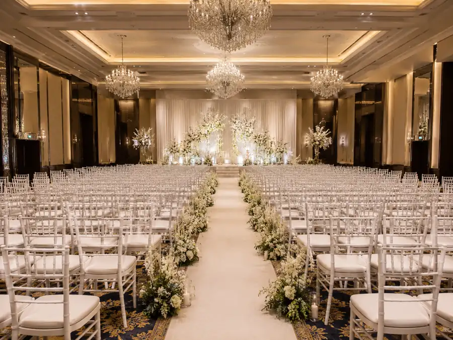 White Chiavari chairs in a ballroom ceremony setup with chandelier lighting and floral aisle