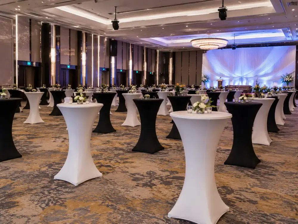 Black and white cocktail tables in a ballroom reception with floral centrepieces