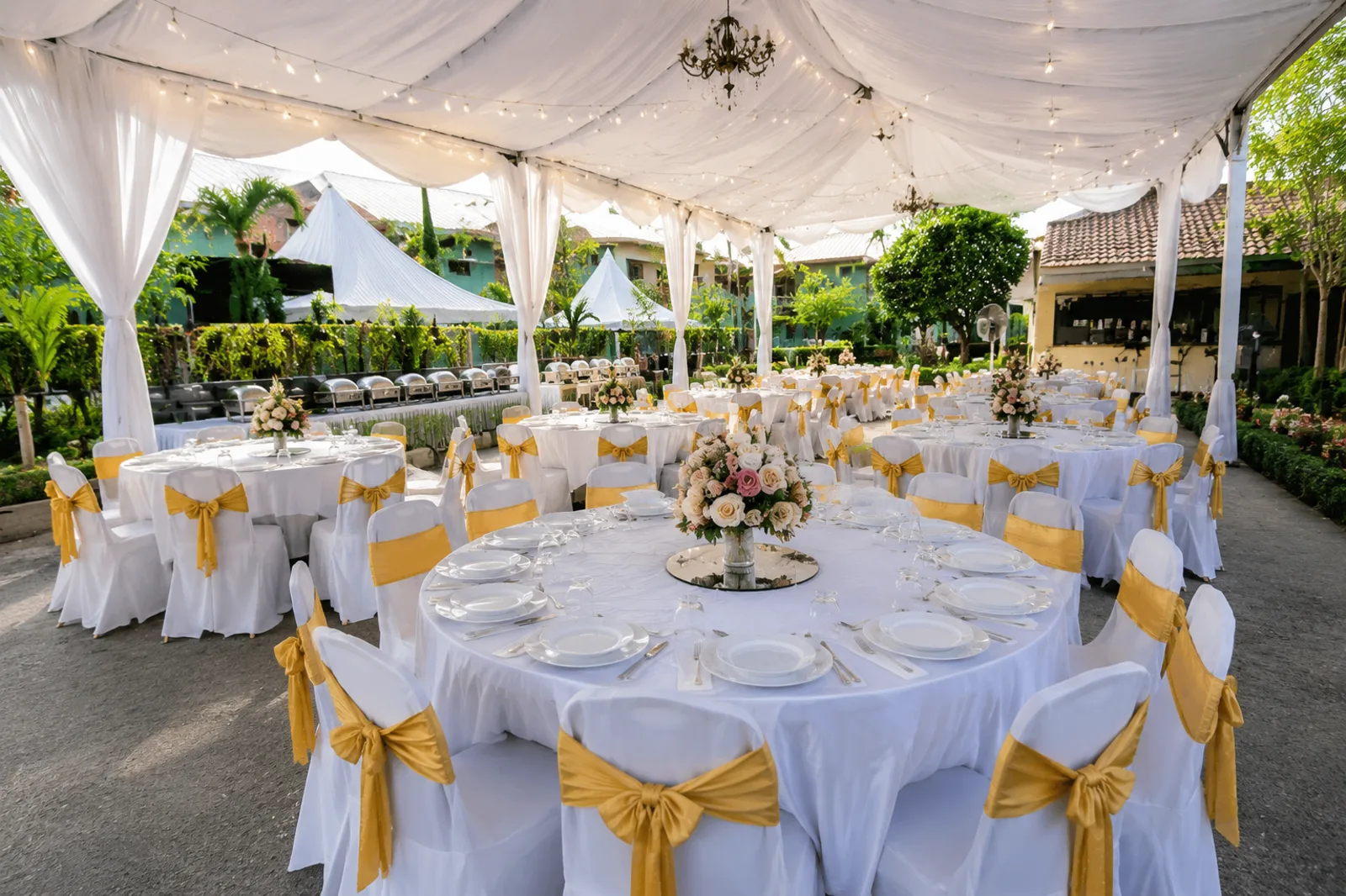 Outdoor canopy wedding round table setup with white cloth and gold chair sash