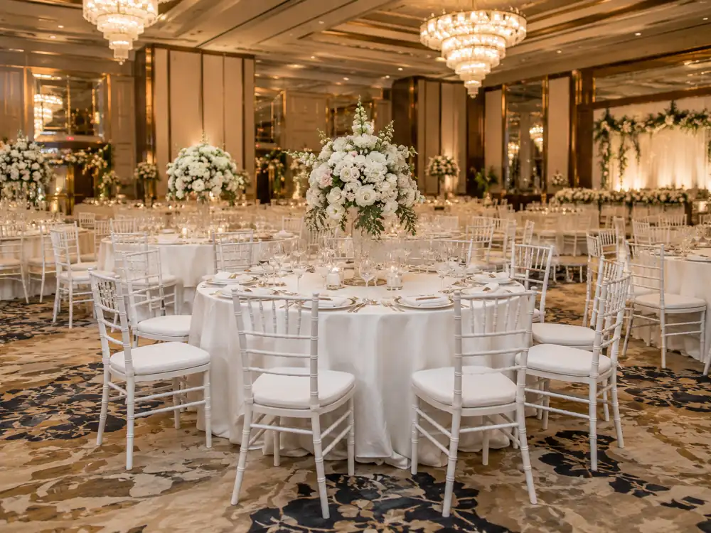 White Tiffany chairs around a formal ballroom dinner table with floral centrepiece