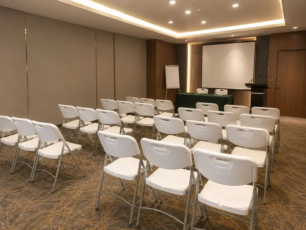 White folding chairs arranged in a seminar room facing a presentation screen